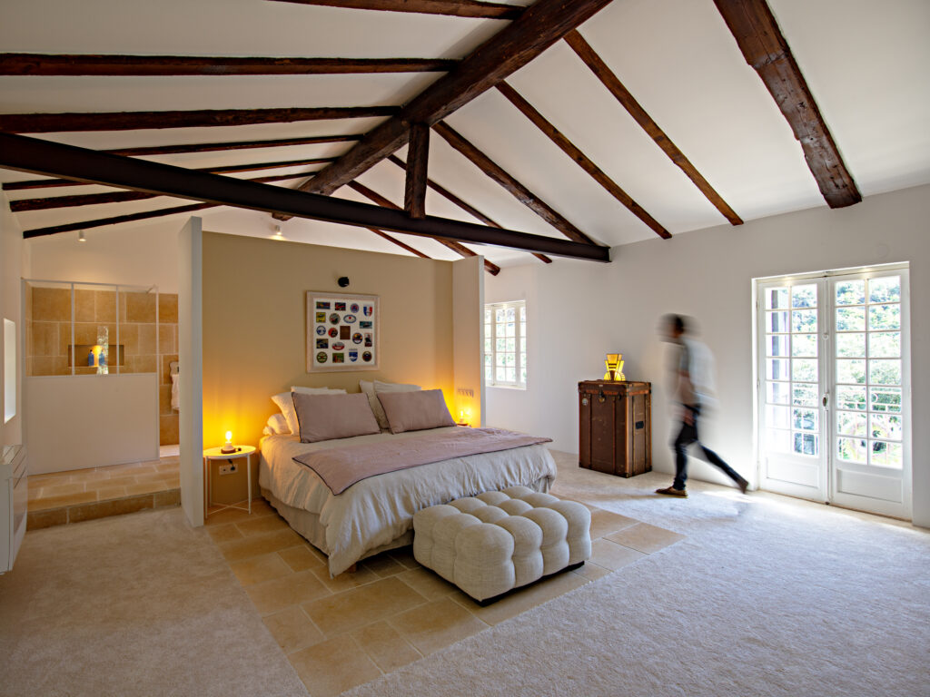 Chambre spacieuse et lumineuse du Mas La Solarie avec lit double, poutres en bois apparentes, salle de bain attenante et vue sur la nature.