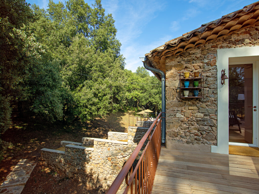 Terrasse du Mas La Solarie donnant sur un cadre naturel verdoyant, avec murs en pierre et ambiance authentique.