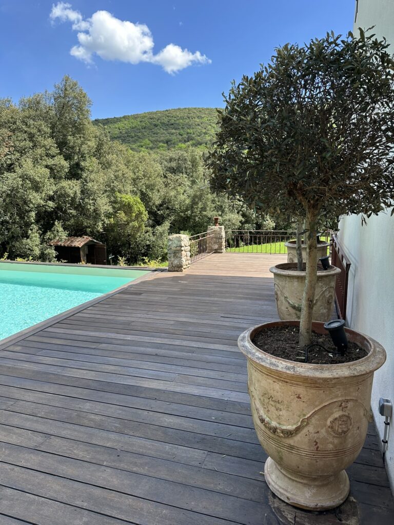 Terrasse en bois avec piscine &agrave; d&eacute;bordement et pots en terre cuite au Mas La Solarie