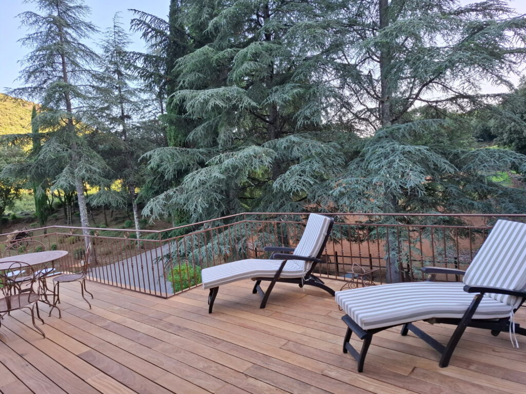 Terrasse en bois du Mas La Solarie avec transats et vue sur les c&egrave;dres